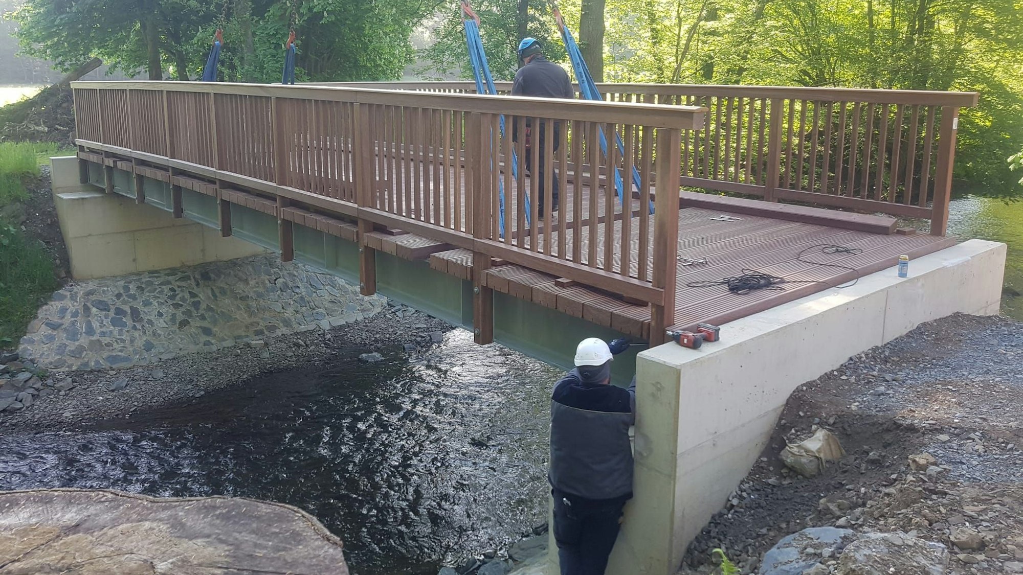Eine neue Brücke über einen Fluss. Monteure arbeiten an ihrer Befestigung.