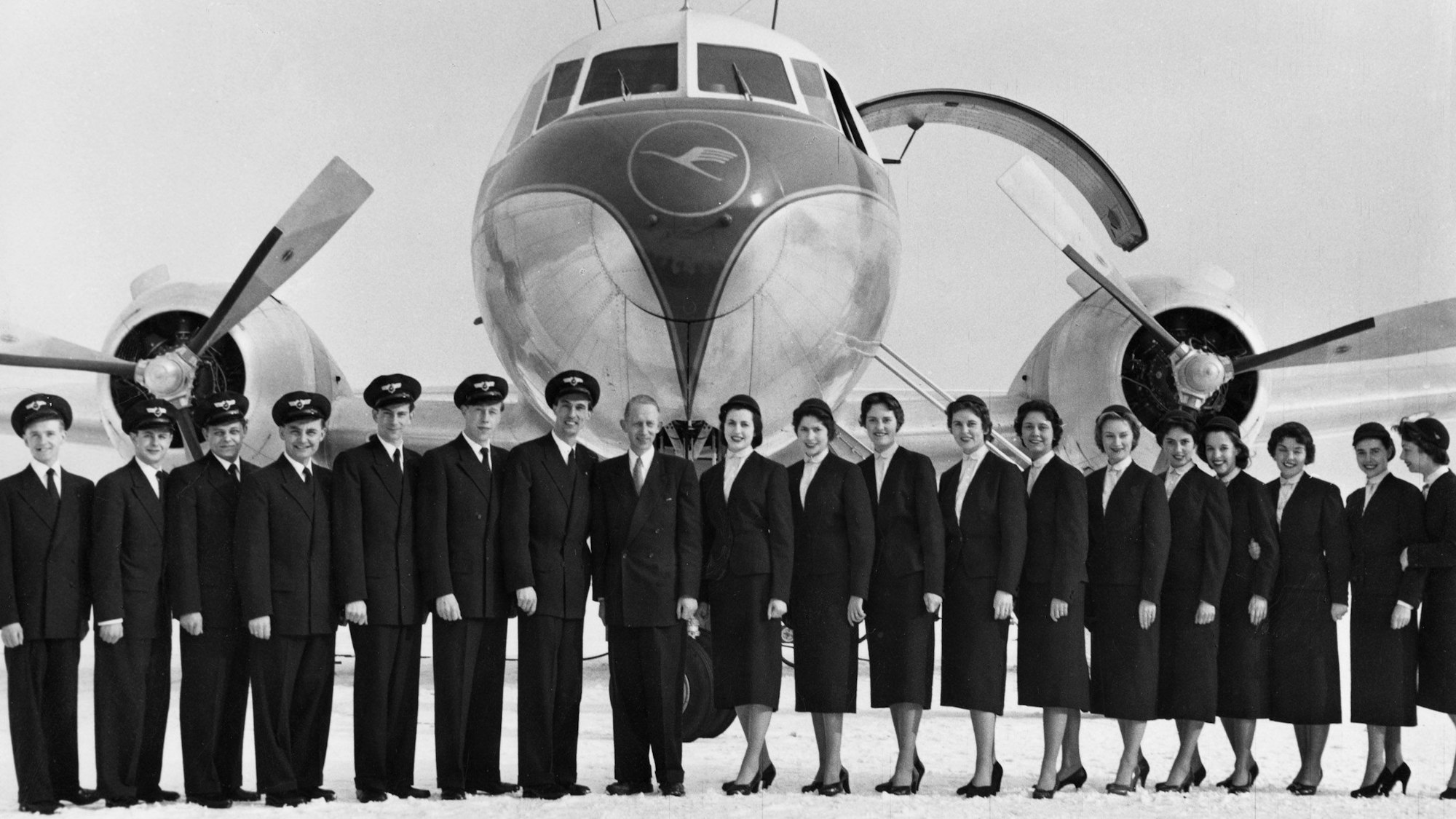 Nach dem Abschluss ihres Lehrgangs warten die ersten Flugbegleiterinnen und Flugbegleiter im Frühjahr 1955 vor einer Convair-Maschine auf ihren Einsatz.