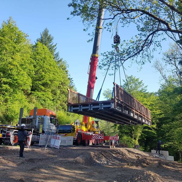 Eine Brücke hängt an einem hohen Kran.
