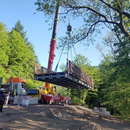 Eine Brücke hängt an einem hohen Kran.
