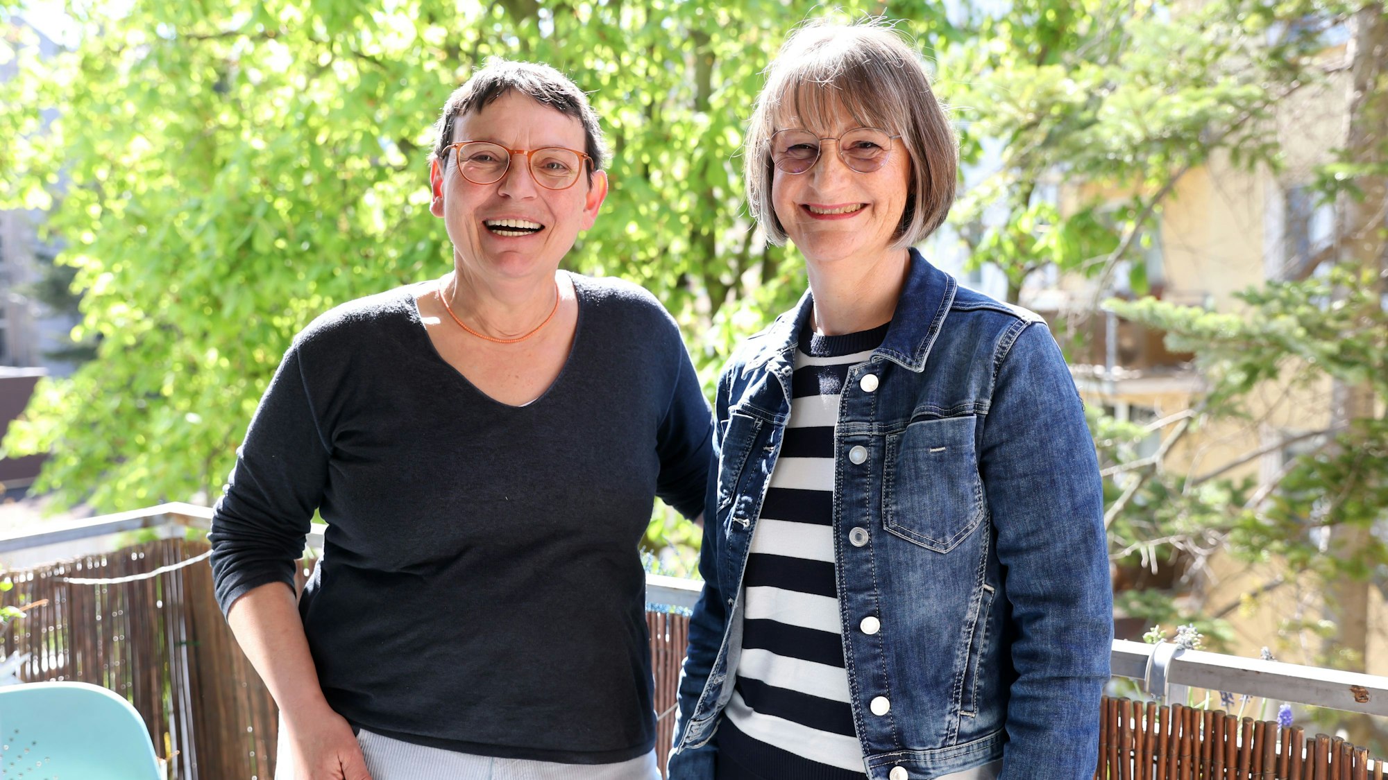Susanne Bösel und Kirsten Hahn stehen auf dem Balkon und lachen in die Kamera.