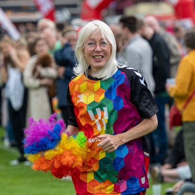 Elfi Scho-Antwerpes im bunten Outfit mit Regenbogen-Pompon in der Hand.