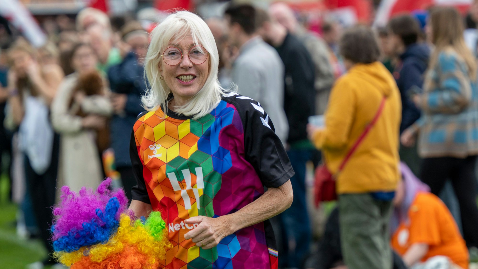 Elfi Scho-Antwerpes im bunten Outfit mit Regenbogen-Pompon in der Hand.