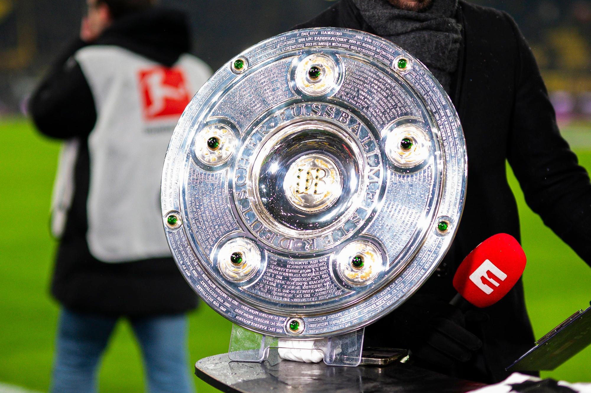 Die Meisterschale steht bei einem Bundesliga-Spiel auf einem Podium.