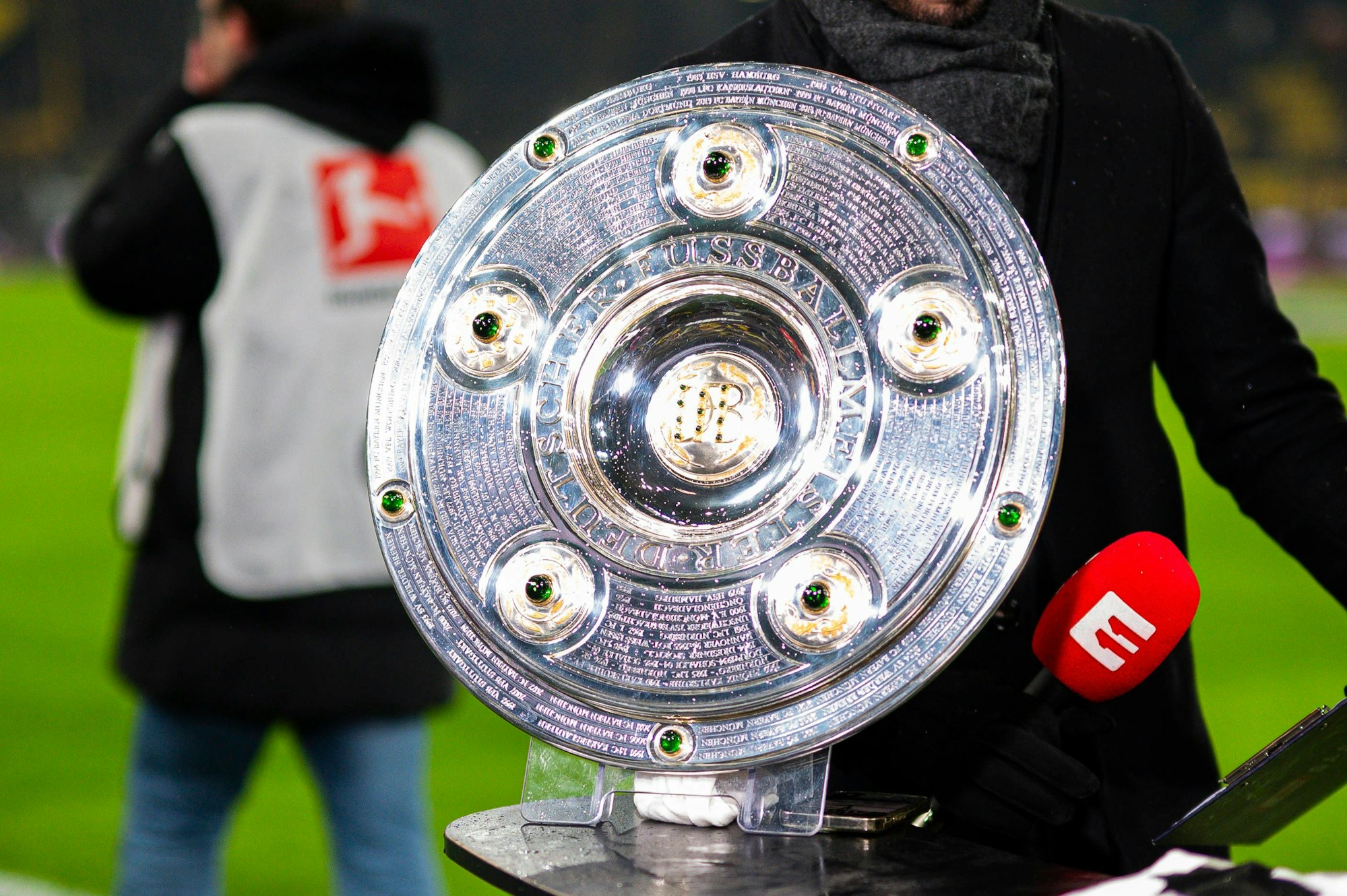 Die Meisterschale steht bei einem Bundesliga-Spiel auf einem Podium.