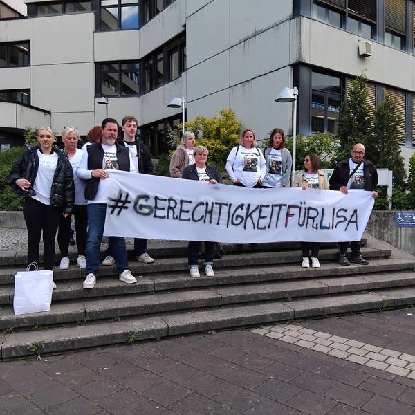 Eine Gruppe steht mit einem Banner auf der Treppe vor dem Amtsgericht