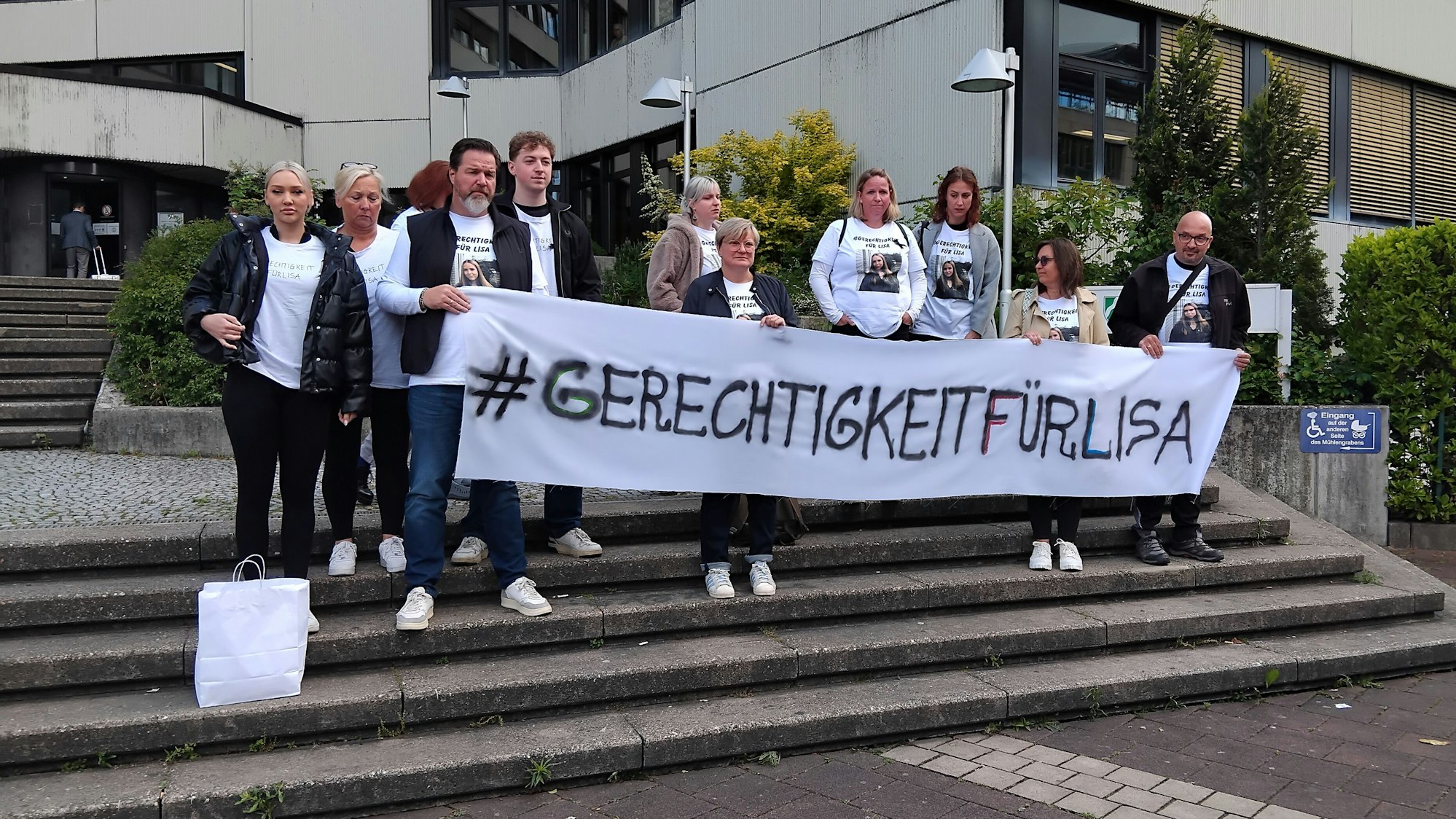Eine Gruppe steht mit einem Banner auf der Treppe vor dem Amtsgericht