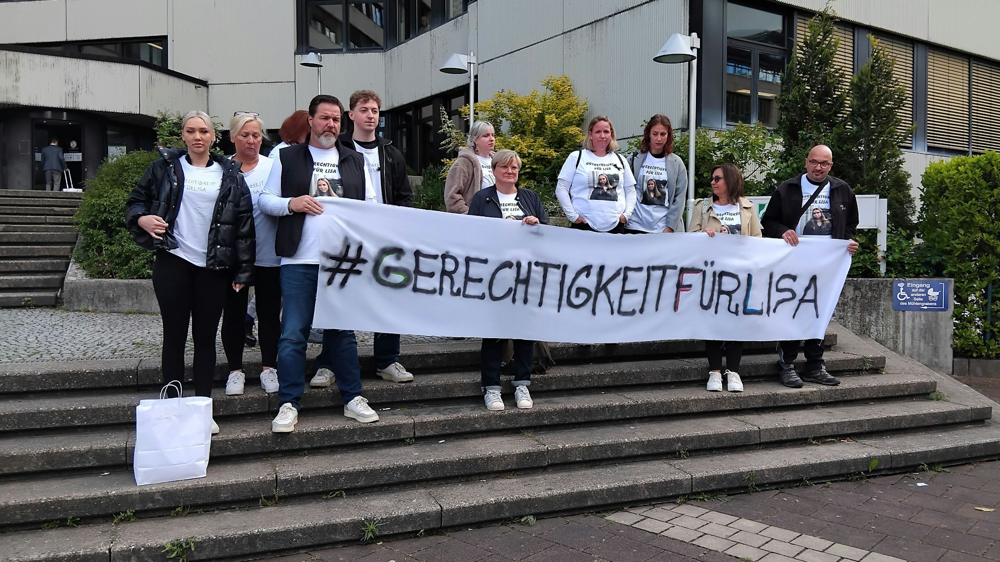 Eine Gruppe steht mit einem Banner auf der Treppe vor dem Amtsgericht