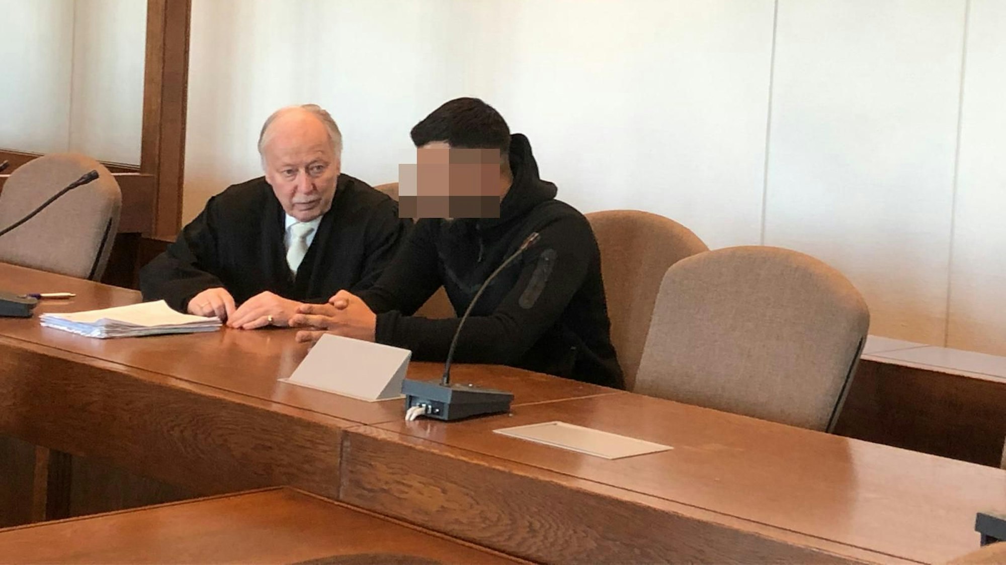 Auf dem Foto sind ein Anwalt und ein Angeklagter zu sehen. Dessen Gesicht ist unkenntlich gemacht.