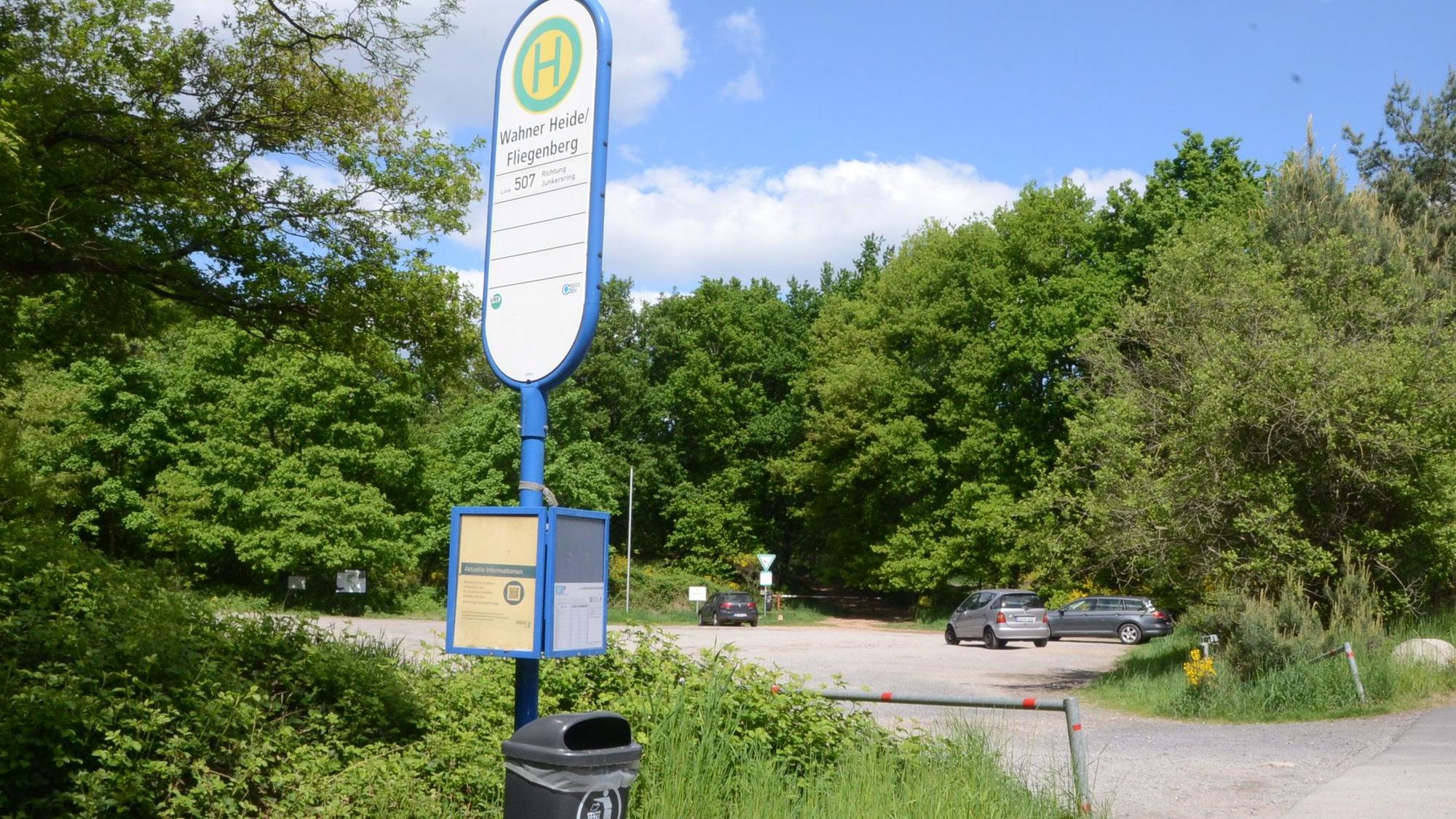 Ein geschotterter Parkplatz und das Hinweisschild für eine Bushaltestelle.