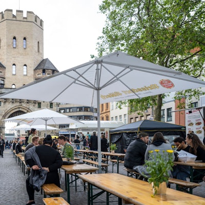 Der Feierabendmarkt auf dem Chlodwigplatz mit Bierbänken- und tischen, drumherum sind Foodtrucks und Getränkestände. (Archivbild 2024)