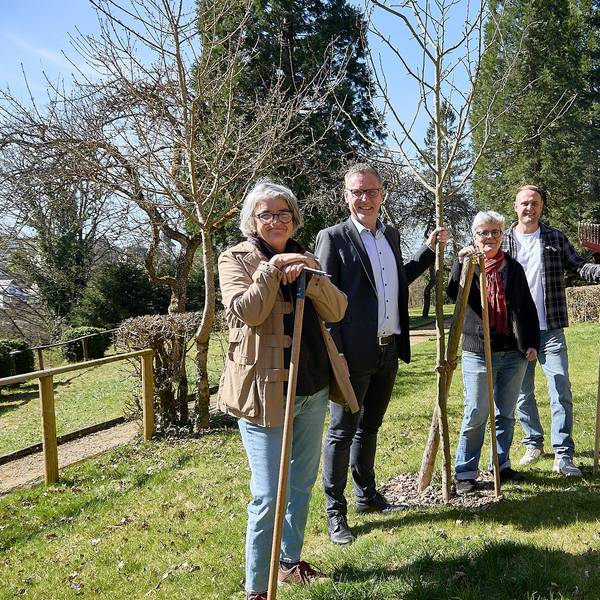 Zwei Frauen und zwei Männer stehen in Nettersheim auf einer Wiese an frisch gepflanzten Bäumen.