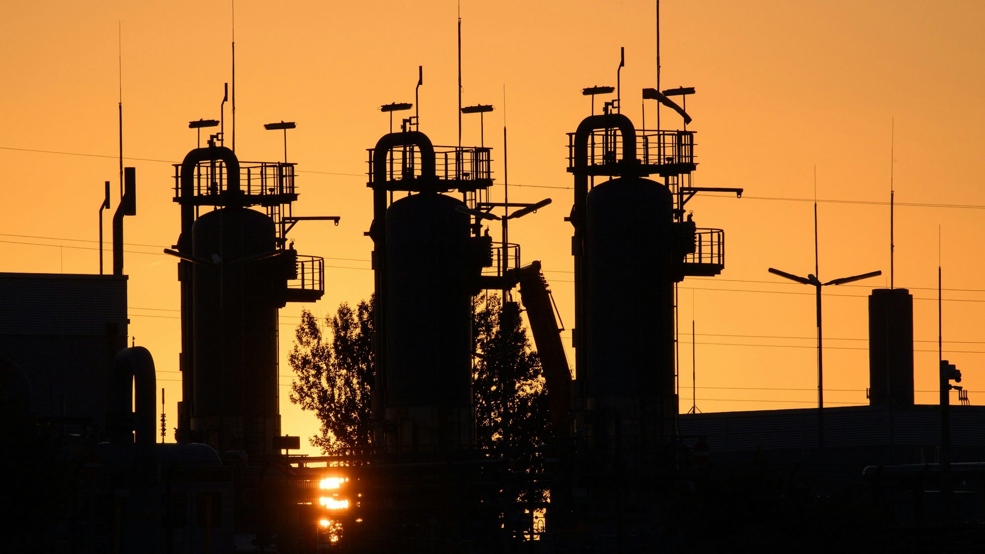 Die Sonne geht hinter technischen Anlagen des Erdgasspeichers Katharina auf.