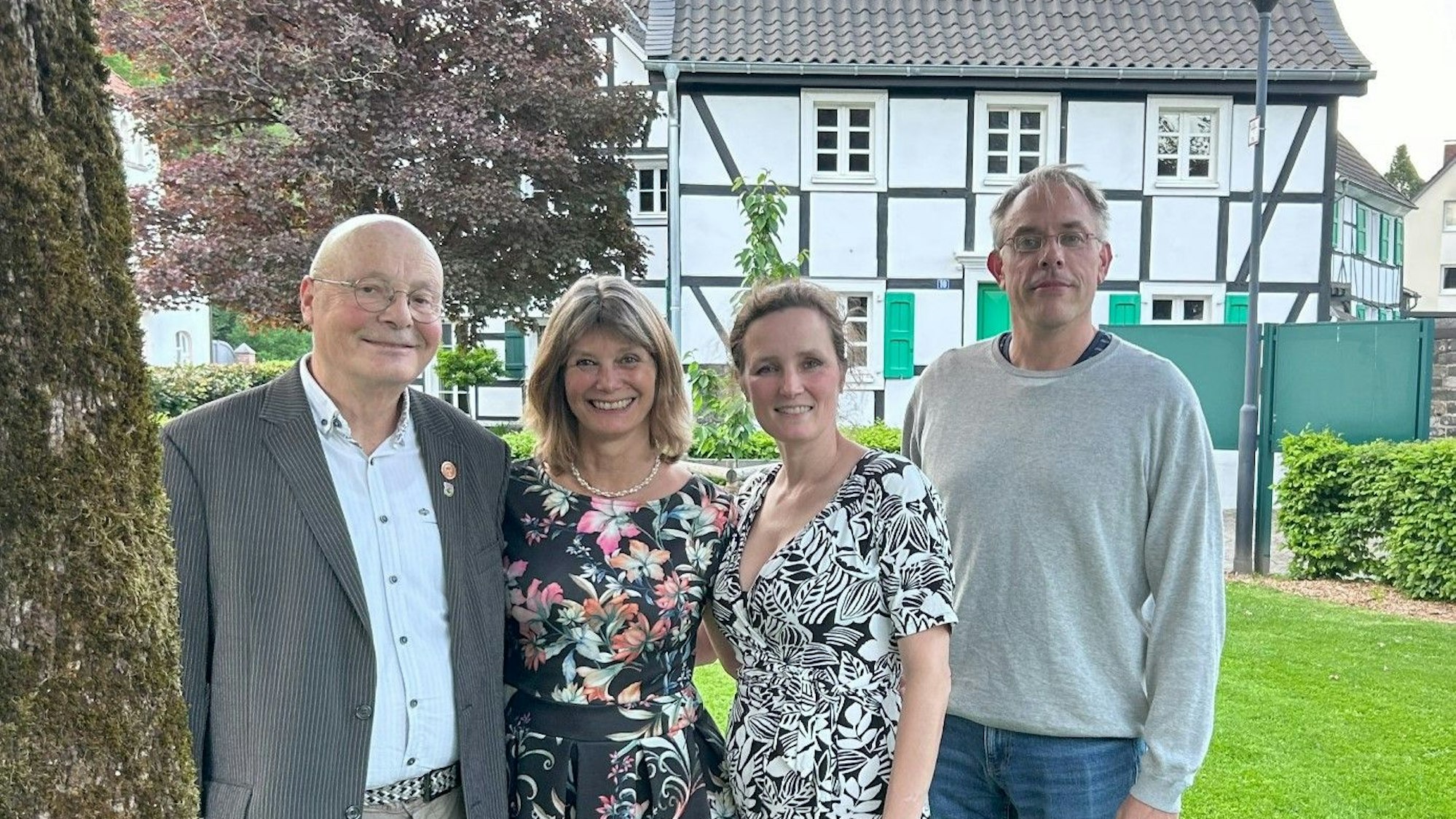 Zwei Männer und zwei Frauen stehen vor einem bergischen Fachwerkhaus.