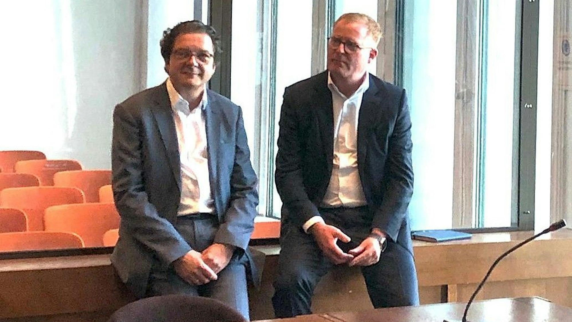 Auf dem Foto sind zwei Männer in einem Gerichtssaal zu sehen.