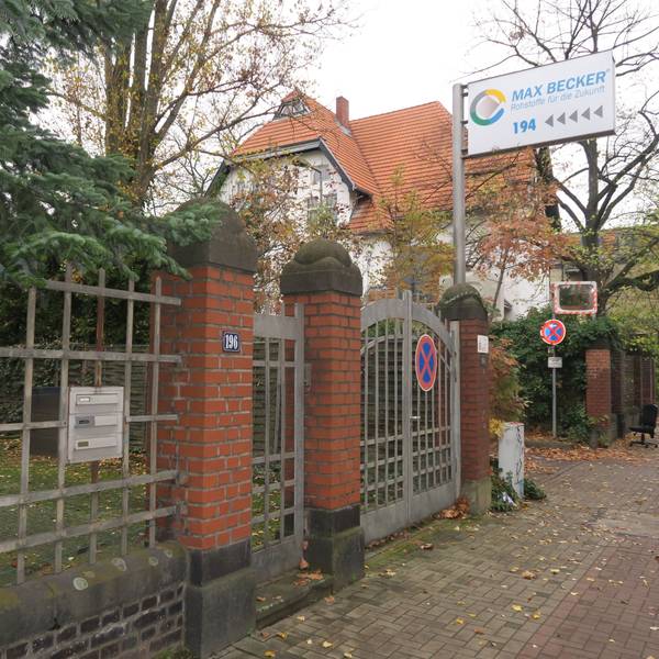 Neben einem Eingangstor aus Stahl und Backstein ist ein Schild auf dem Max Becker Rohstoffe für die Zukunft steht.