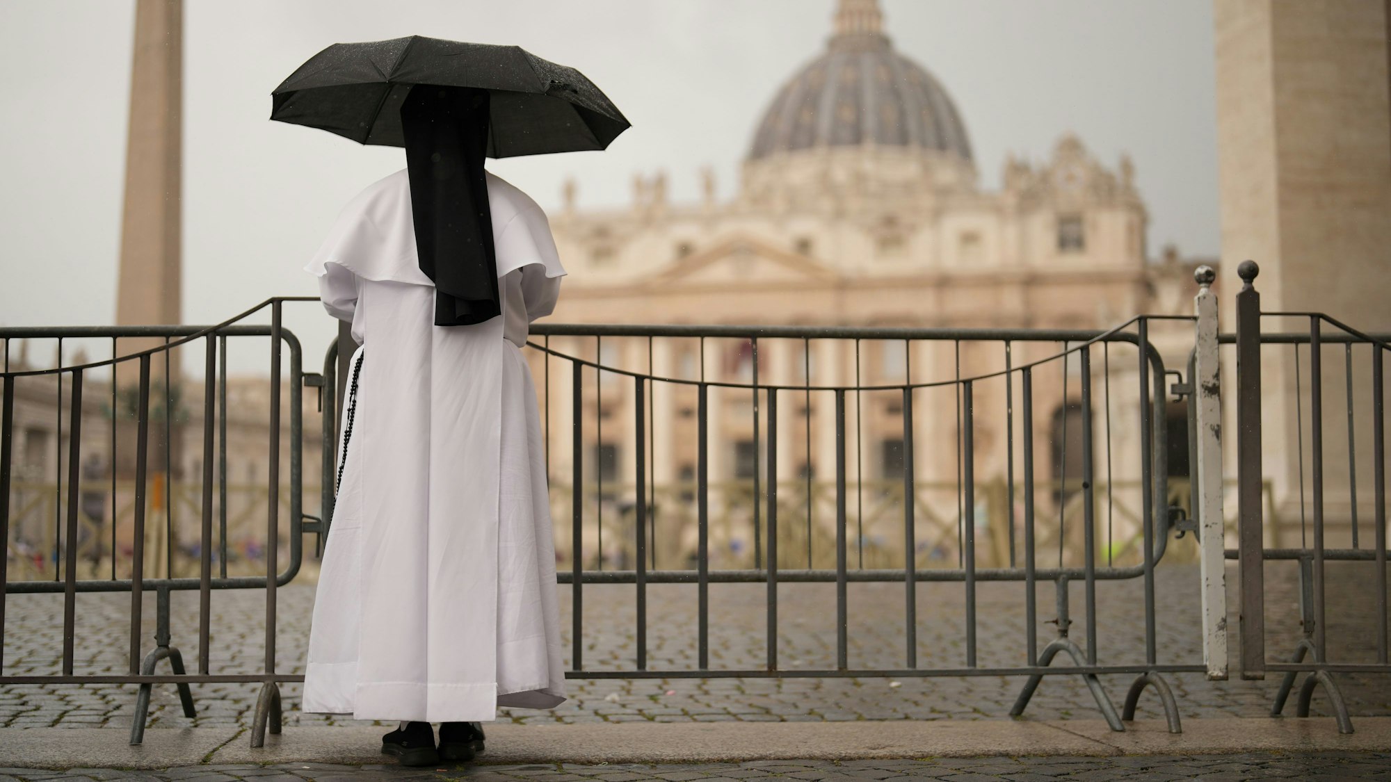 07.05.2025, Vatikan, Vatikanstadt: Eine Nonne schützt sich vor dem Regen, während sie die letzte Messe der Kardinäle im Petersdom vor dem Konklave zur Wahl eines neuen Papstes auf dem Petersplatz verfolgt. Foto: Francisco Seco/AP/dpa +++ dpa-Bildfunk +++