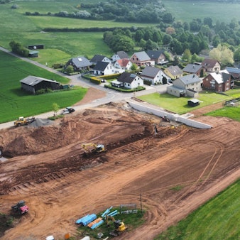 Die Drohnenaufnahme zeigt die Baustelle eines Regenrückhaltebeckens und im Hintergrund den Ort Kallmuth.