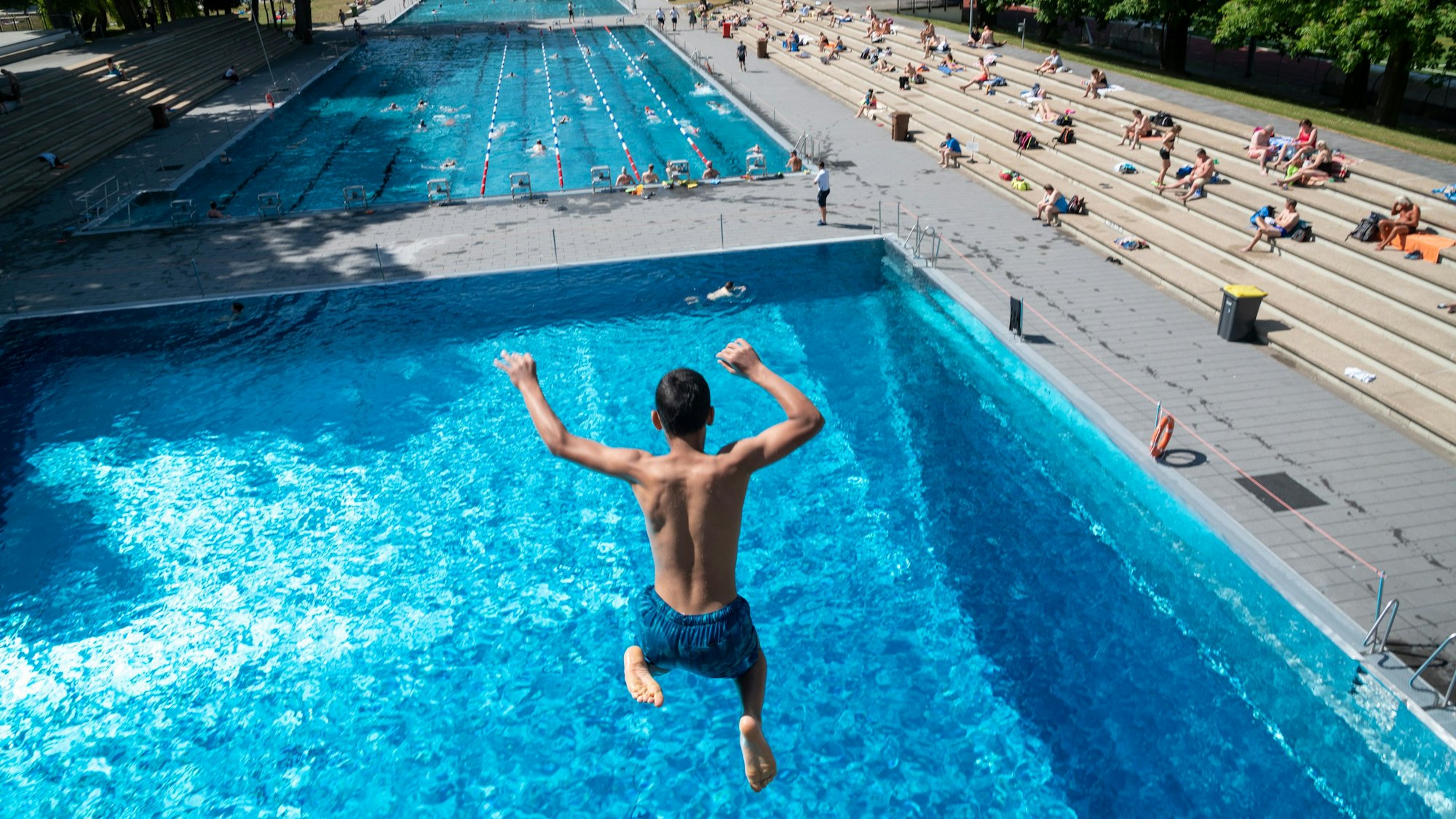 Ein Junge springt vom Stadionbad vom Sprungturm.
