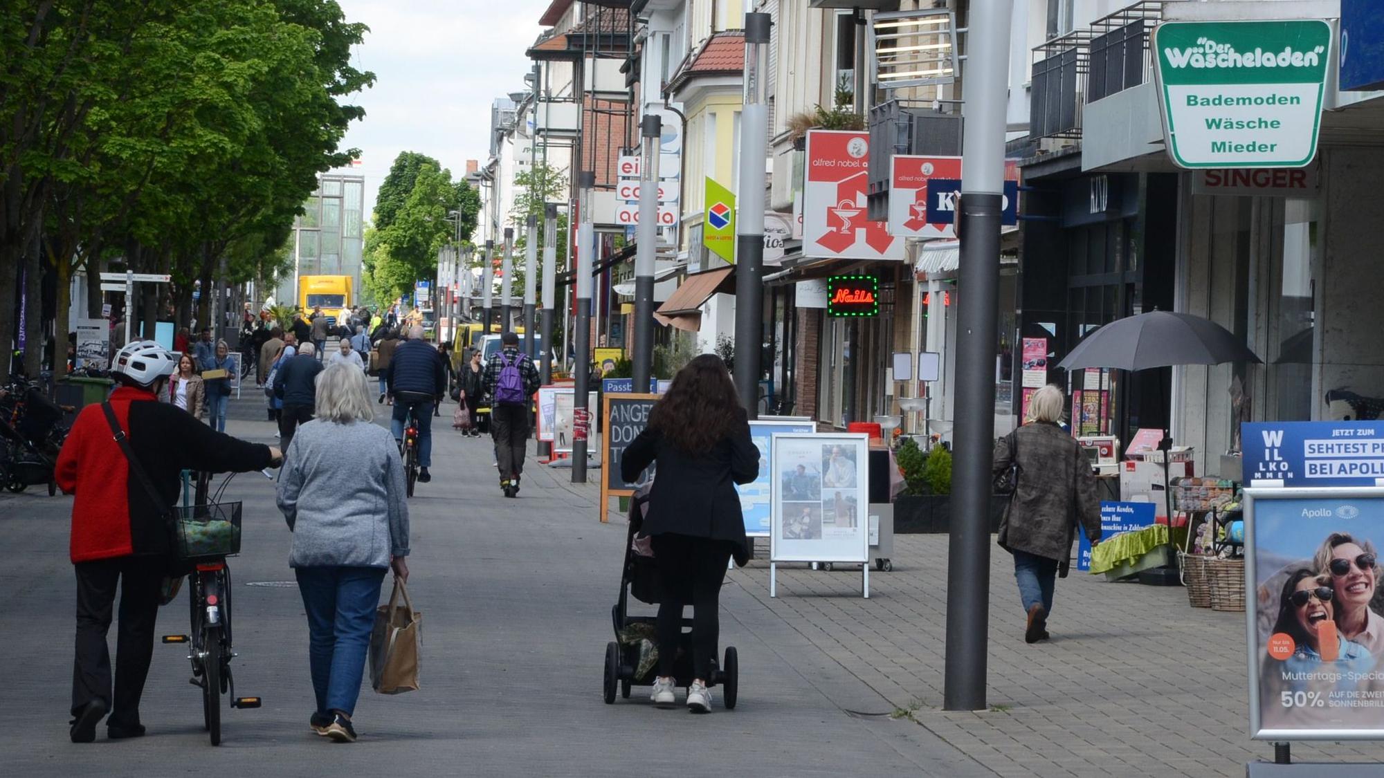 Menschen flanieren in einer Fußgängerzone.