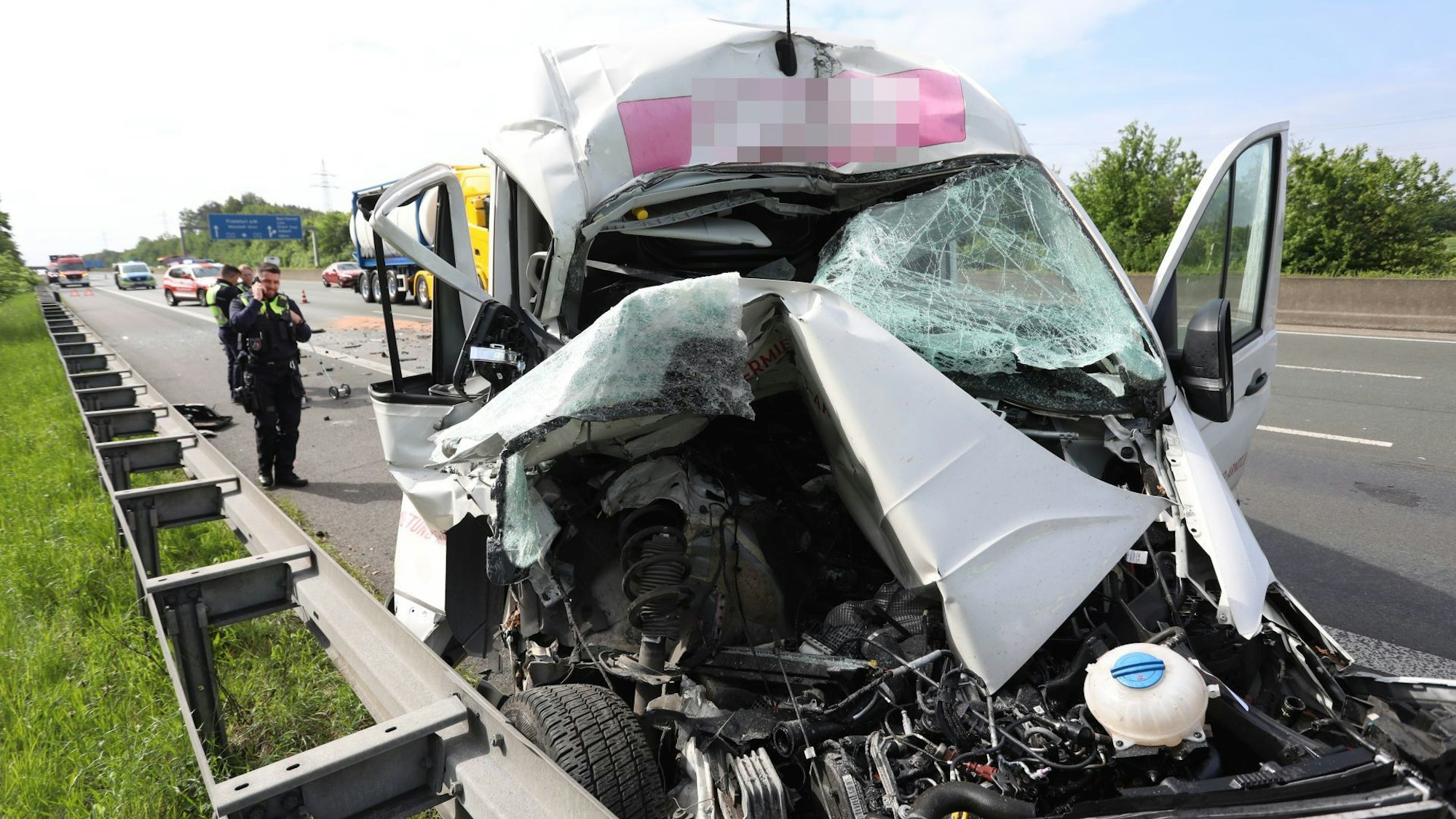 Ein stark zerstörtes Fahrzeug auf dem Standstreifen einer Autobahn.