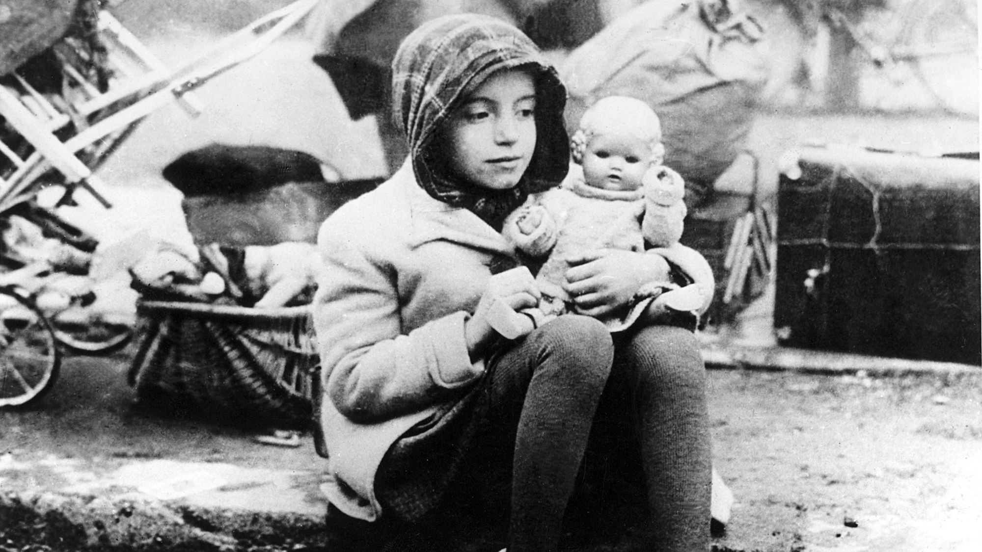Ein Mädchen aus einem Flüchtlingstreck mit ihrer Puppe im Arm in den Wirren der Nachkriegszeit.