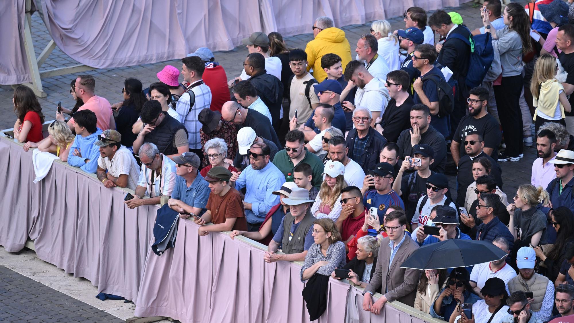 Menschen stehen kurz vor Beginn des Konklave zur Wahl eines neuen Papstes auf dem Petersplatz.