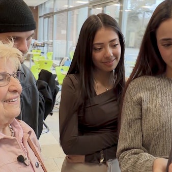 Marianne Blasberg und Schülerinnen schauen auf ein Tablet