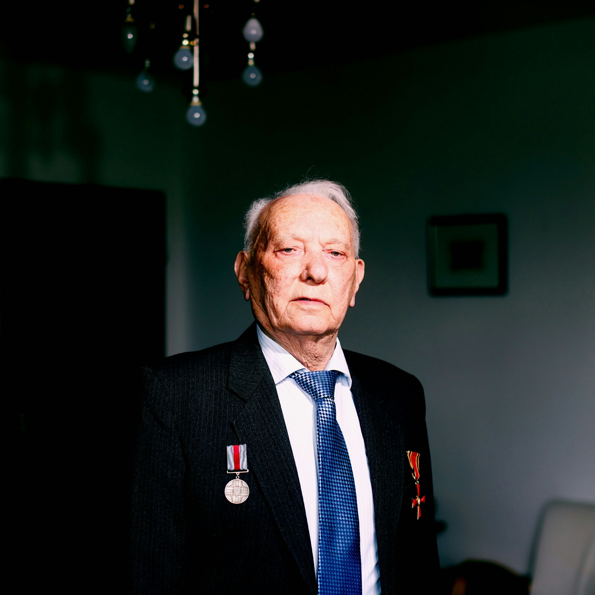 Roman Shvartsman, fotografiert in seiner Wohnung in Köln. Er trägt zwei Orden am Revers.