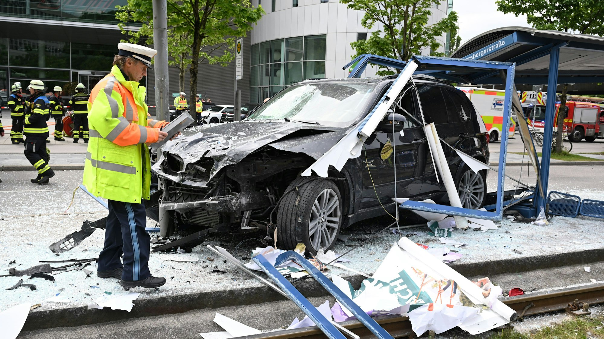 Ein Polizist steht in München neben dem Unfallfahrzeug in den Glassplittern einer Haltestelle.