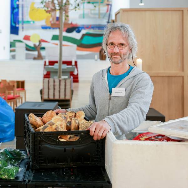 Hanno Sprissler ist in seiner Kirche mit einer Kiste Brot zu sehen.
