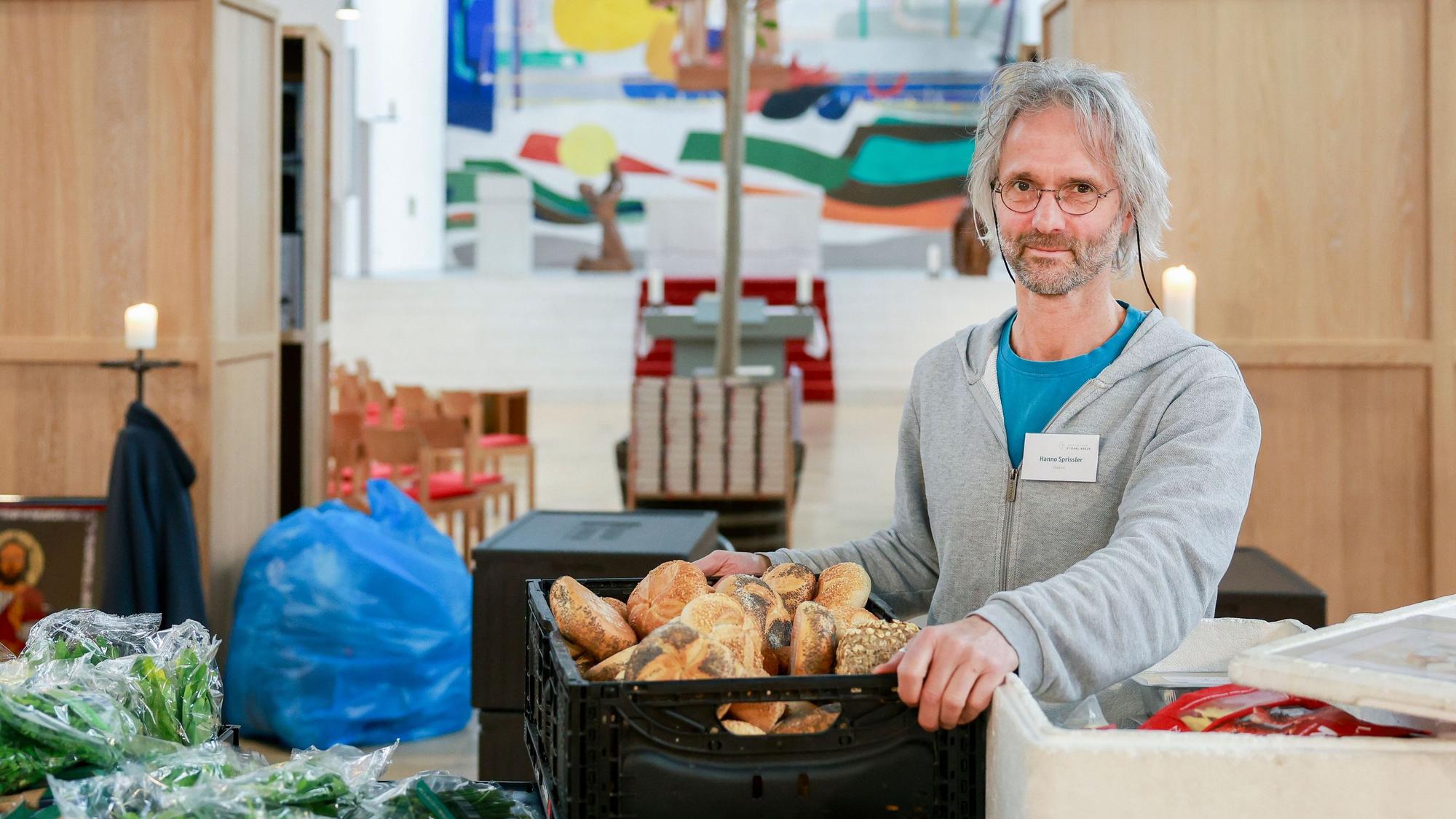 Hanno Sprissler ist in seiner Kirche mit einer Kiste Brot zu sehen.