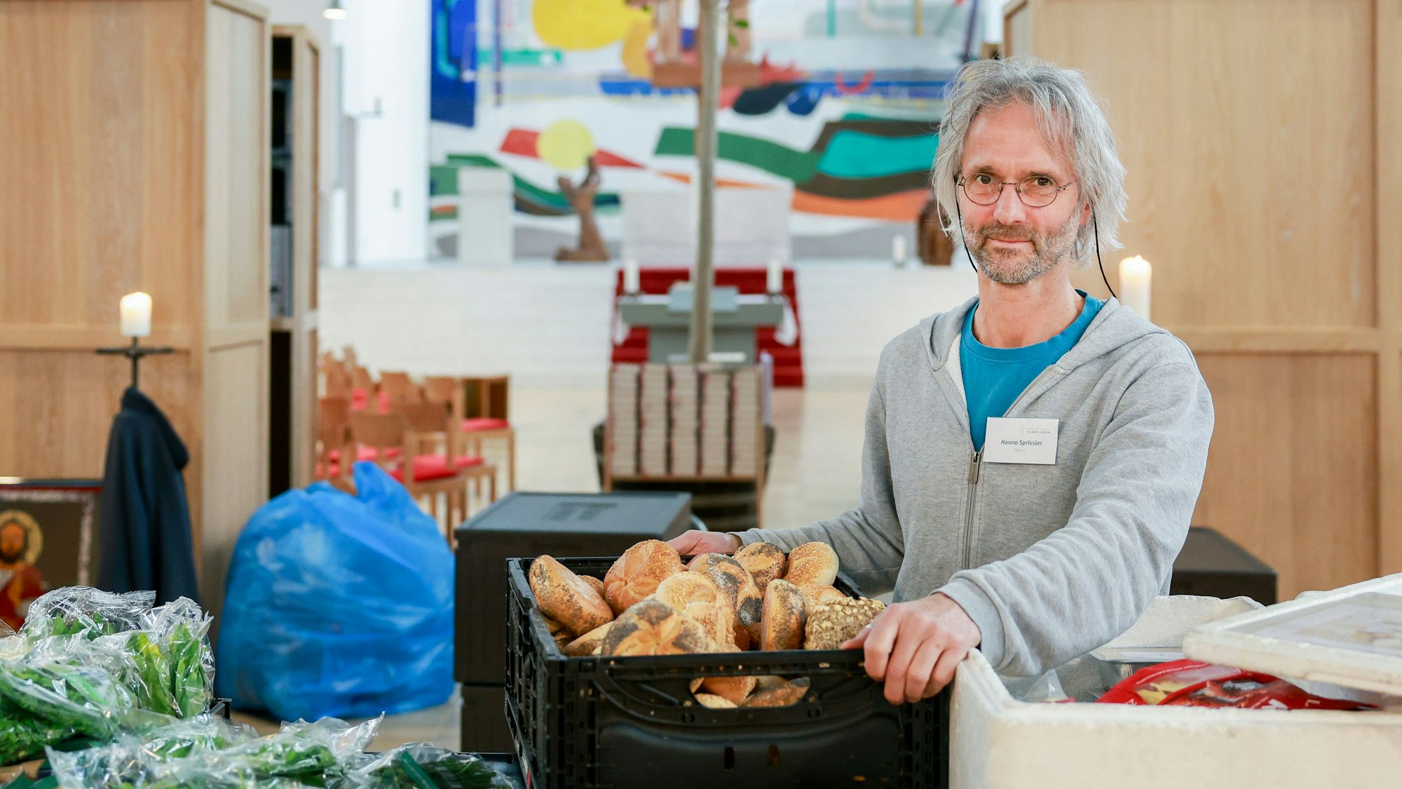 Hanno Sprissler ist in seiner Kirche mit einer Kiste Brot zu sehen.