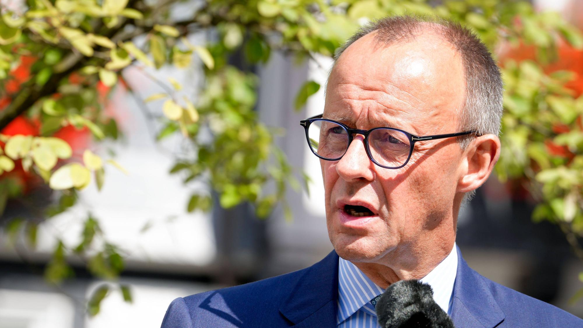Friedrich Merz spricht in der Sonne in ein Mikrofon.
