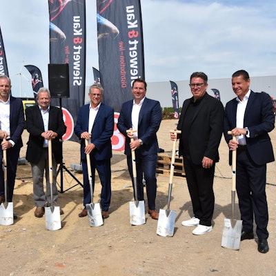 Auf dem Bild sind Männer in Anzügen zu sehen, die einen Spaten halten.