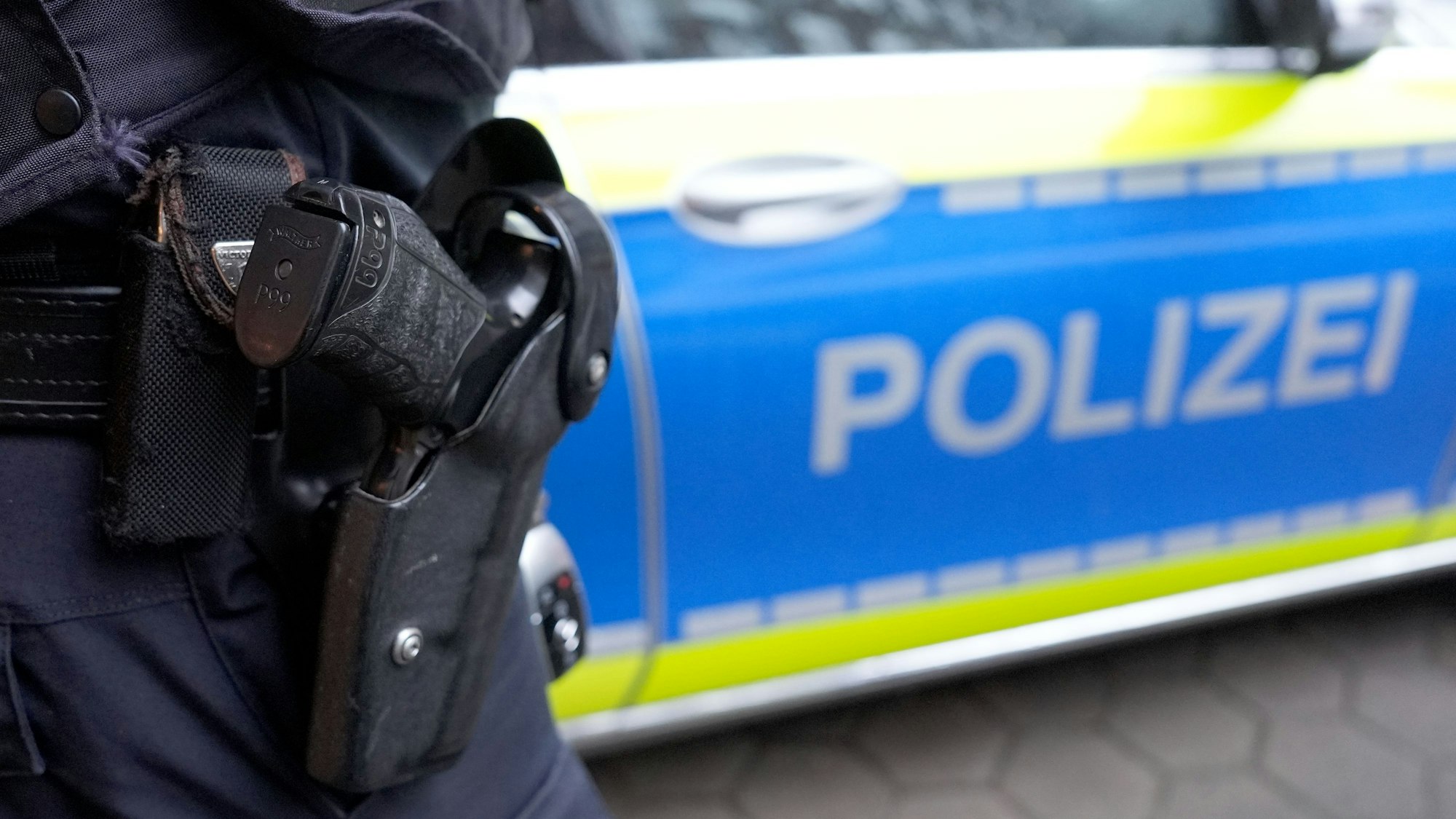 Das Foto zeigt einen Polizisten vor einem Einsatzwagen.