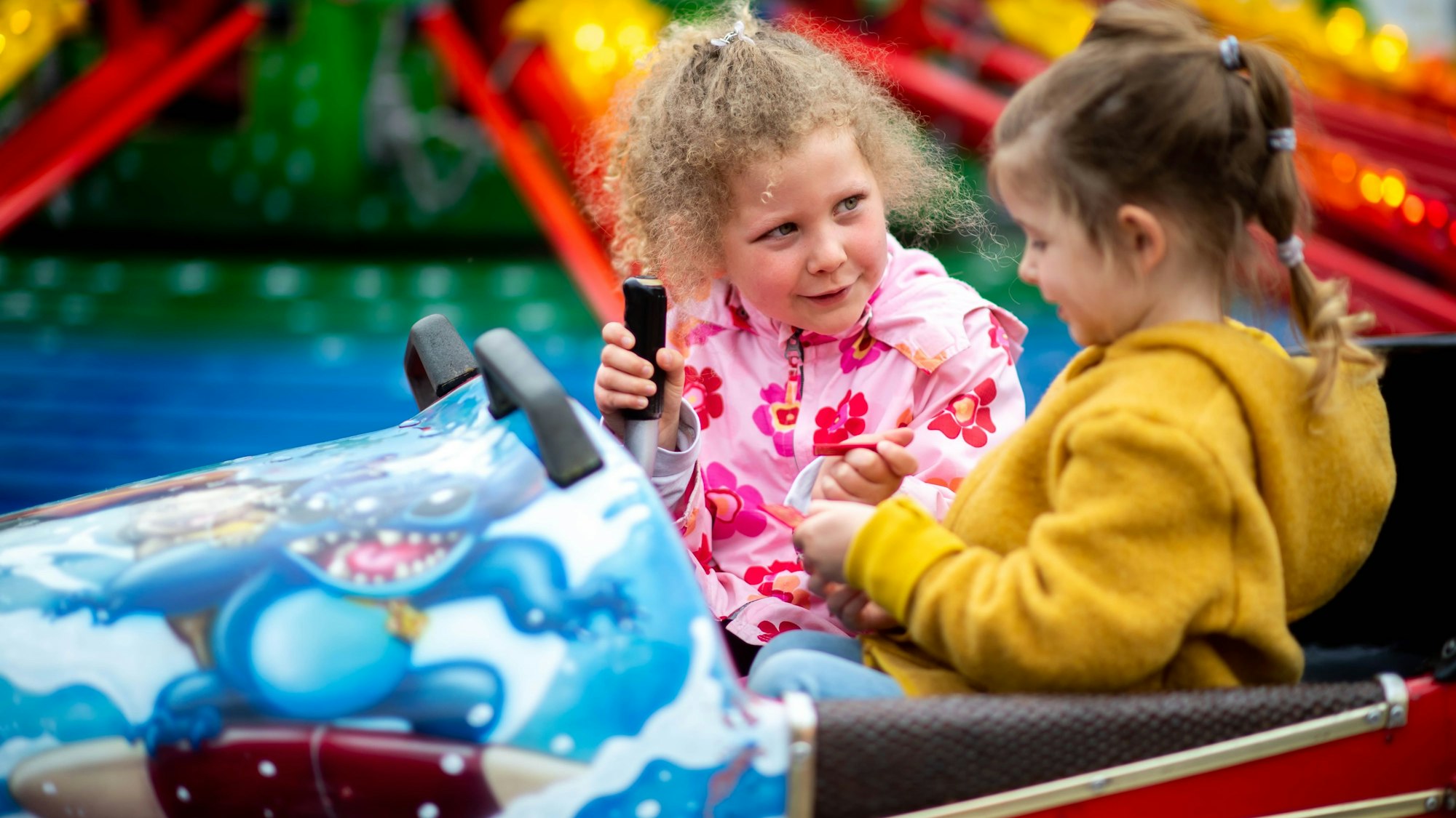 Zwei Mädchen sitzen in einem Fahrgeschäft und haben Spaß an der Kirmes in Euskirchen.