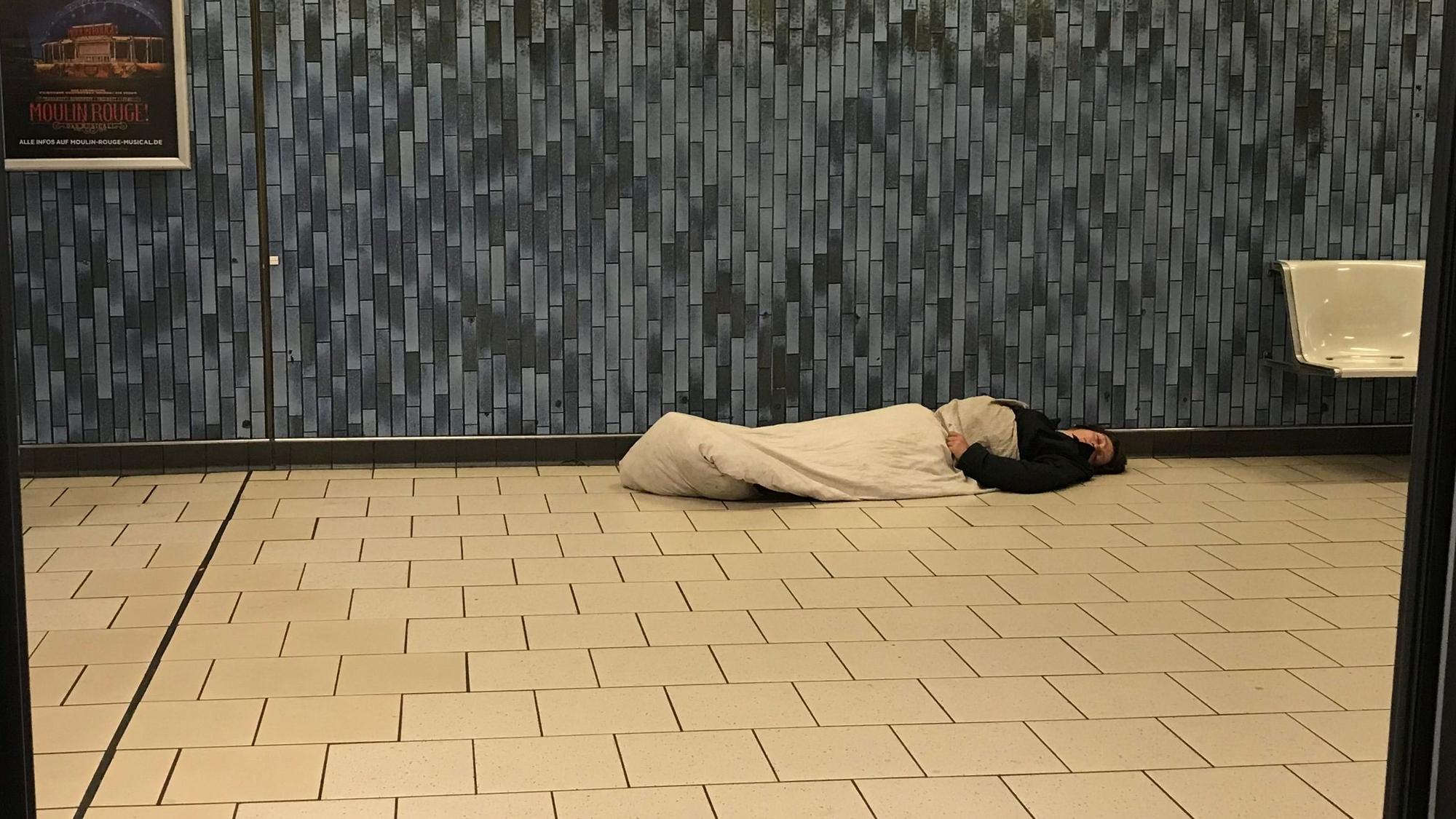 Das Bild zeigt einen schlafenden Obdachlosen im Kölner Hauptbahnhof