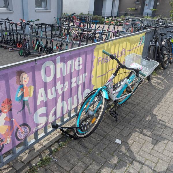 Das Foto zeigt große Spruchbanner am Zaun vor dem Fahrrad- und Rollerabstellplatz.