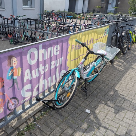 Das Foto zeigt große Spruchbanner am Zaun vor dem Fahrrad- und Rollerabstellplatz.