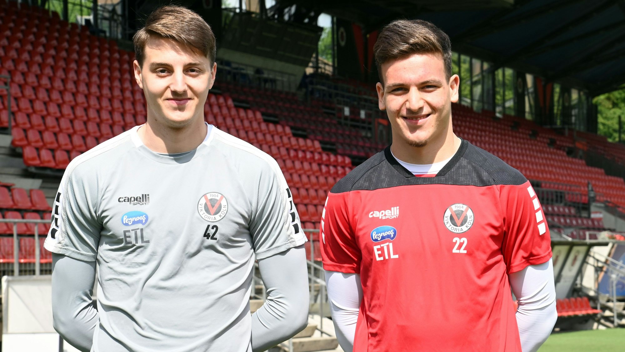 Zwei Fußballer stehen nebeneinander in einem Stadion.