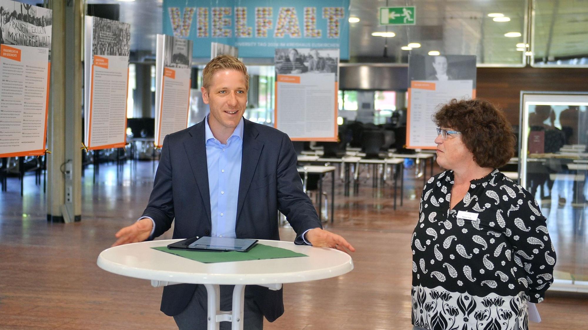 Landrat Markus Ramers und Kreisarchivarin Heike Pütz stehen nebeneinander an einem Stehtisch vor einer Ausstellung.