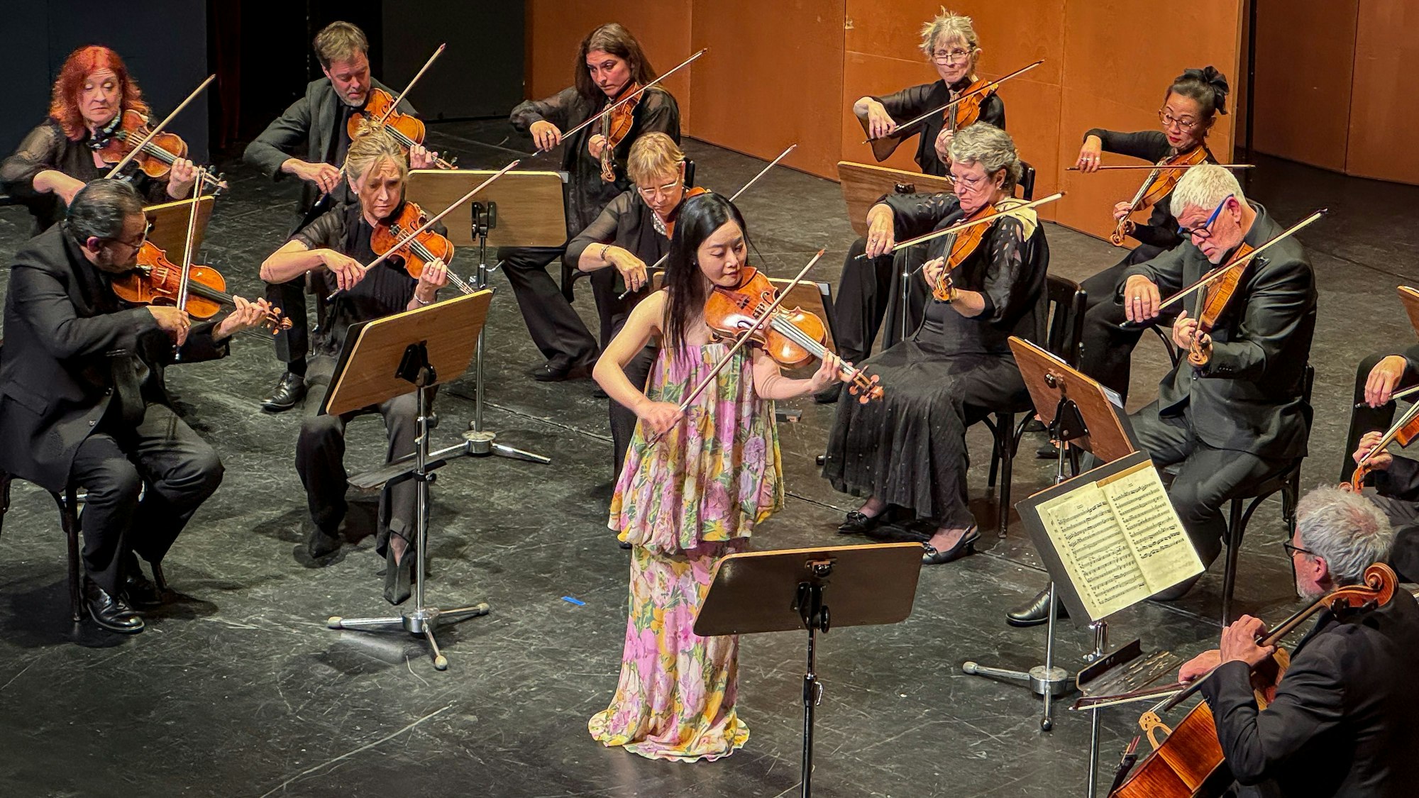 Eine Geigerin auf der Bühne mit einem Orchester.