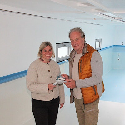 Wolfgang Schmitz vom Kreissportbund Düren und Blankenheims Bürgermeisterin Jennifer Meuren stehen im Schwimmbad-Container. Sie halten das Narwali-Maskottchen in der Hand.