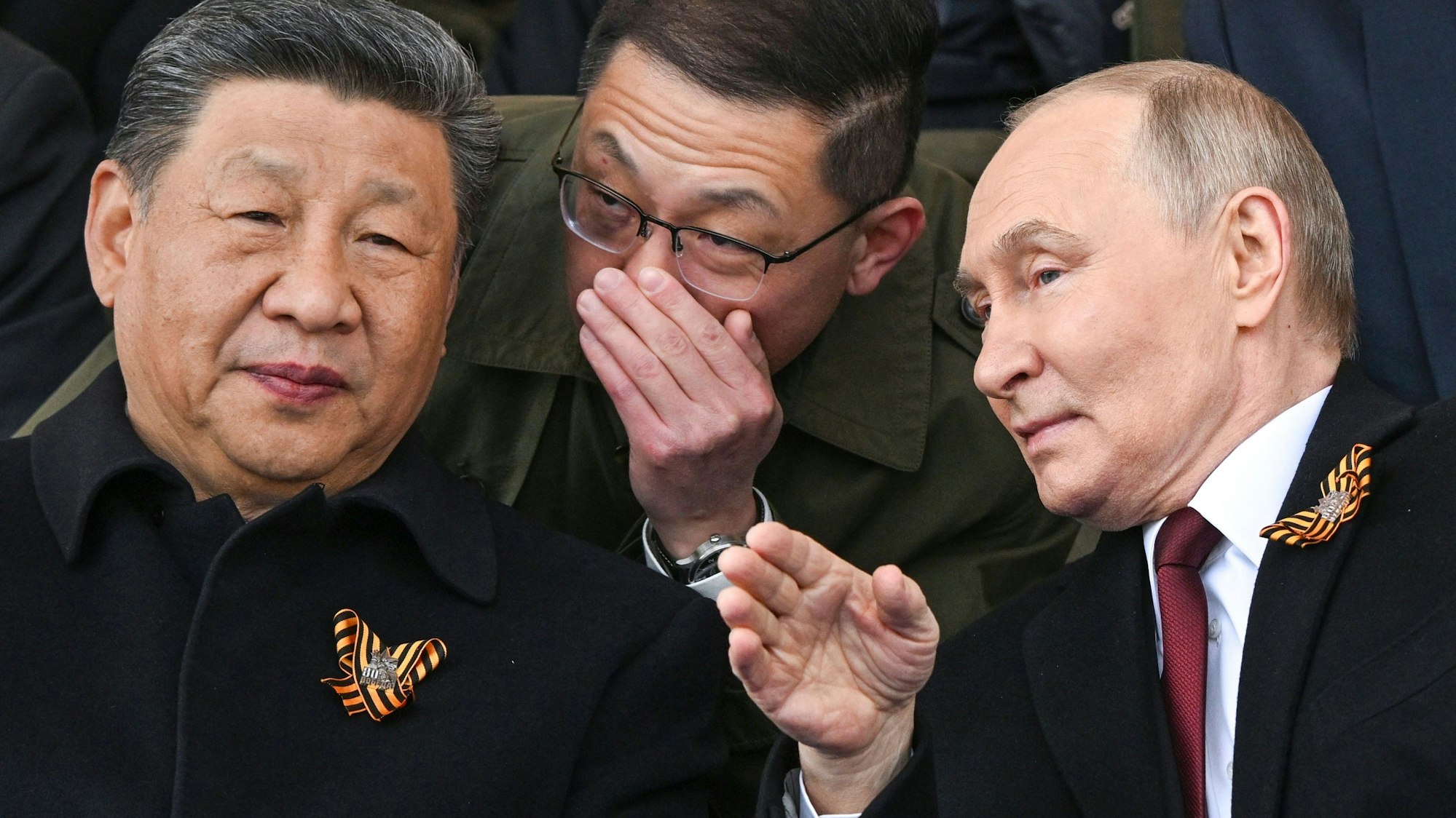09.05.2025, Russland, Moskau: Der russische Präsident Wladimir Putin (r) und der chinesische Präsident Xi Jinpin (l) unterhalten sich während der Militärparade zum Tag des Sieges, anlässlich der Feierlichkeiten zum 80. Jahrestag des Sieges der Sowjetunion über Nazi-Deutschland im Zweiten Weltkrieg. Foto: Sergei Bobylev/Photo host agency RIA Novosti/AP/dpa +++ dpa-Bildfunk +++