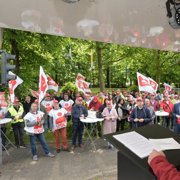 IGBCE-Gewerkschaftssekretär Thomas John Dyer spricht vor dem Werkstor von Isover in Bergisch Gladbach zu Protestierenden.