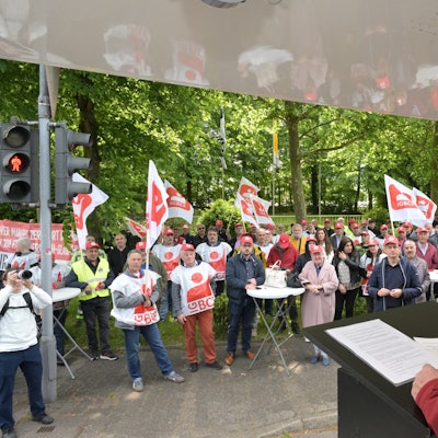 IGBCE-Gewerkschaftssekretär Thomas John Dyer spricht vor dem Werkstor von Isover in Bergisch Gladbach zu Protestierenden.