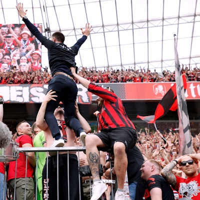 Das Bild zeigt Xabi Alonso nach der Meisterschaft 2024 auf dem Zaun in der Nordkurve der Bay-Arena.