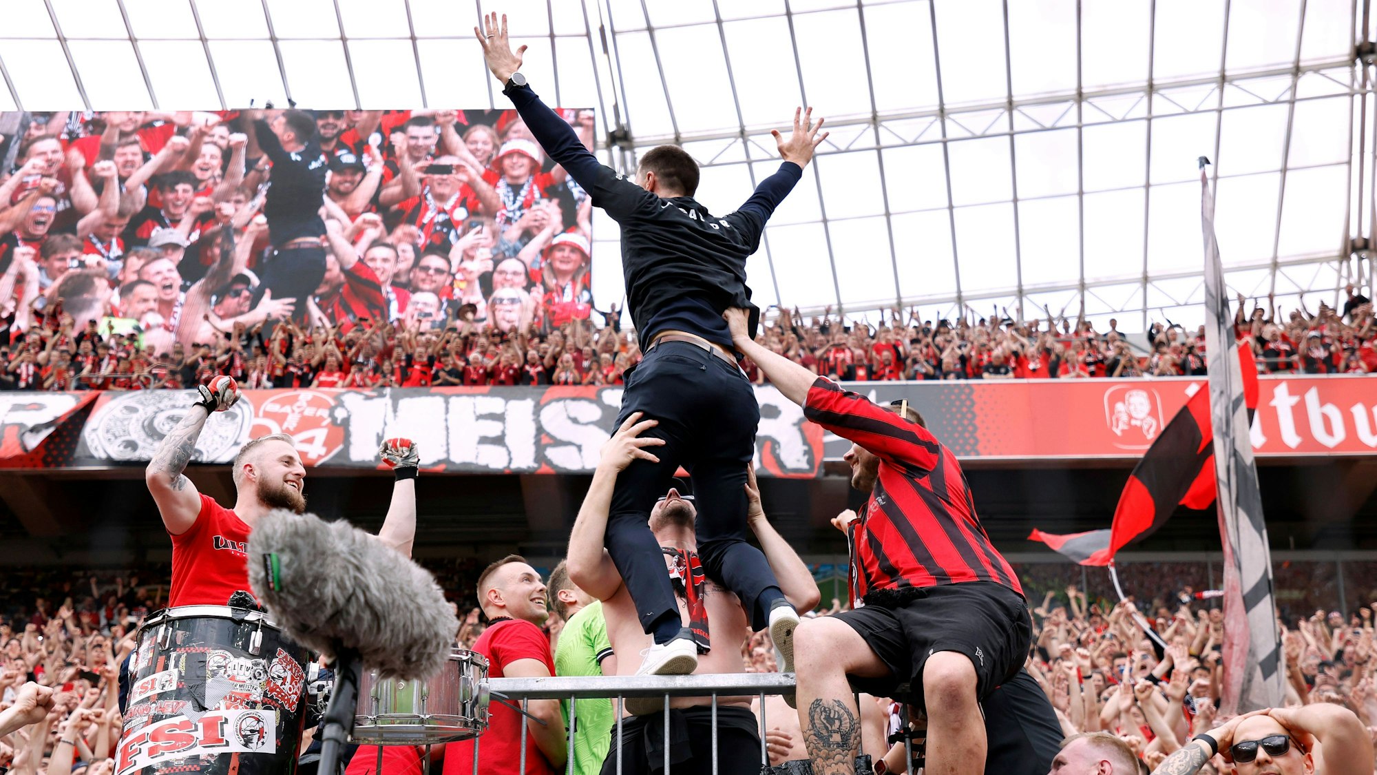 Das Bild zeigt Xabi Alonso nach der Meisterschaft 2024 auf dem Zaun in der Nordkurve der Bay-Arena.