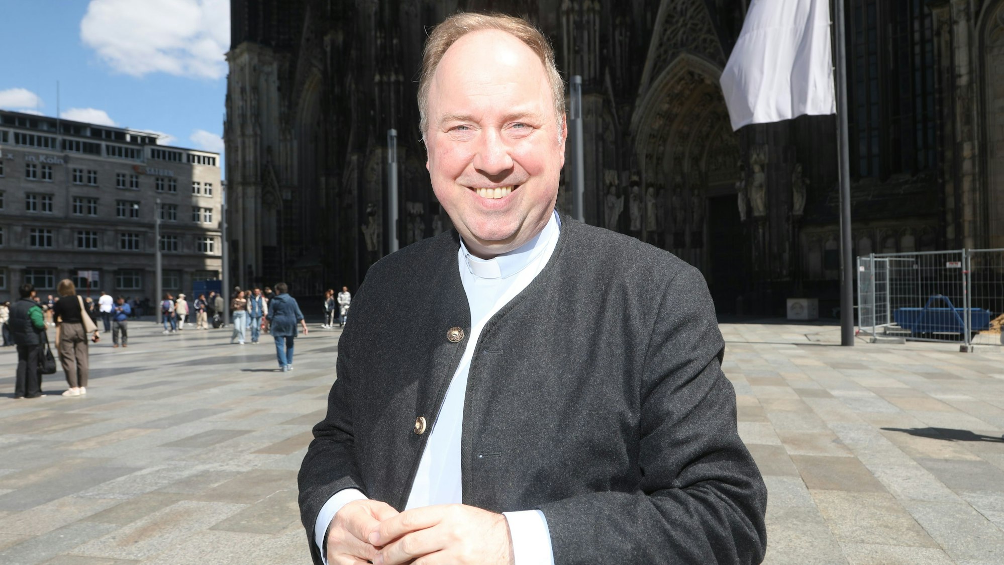 Robert Kleine steht auf der Domplatte vor dem Kölner Dom und lächelt in die Kamera.